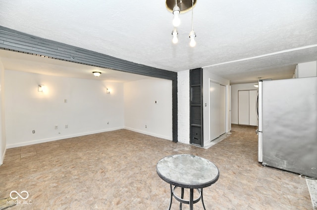 basement featuring stainless steel fridge and a textured ceiling