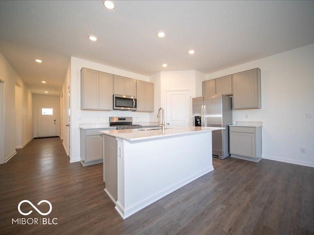 kitchen with sink, appliances with stainless steel finishes, dark hardwood / wood-style flooring, gray cabinets, and a kitchen island with sink