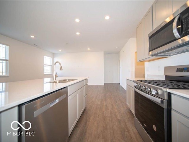 kitchen with stainless steel appliances, white cabinetry, sink, and dark hardwood / wood-style floors