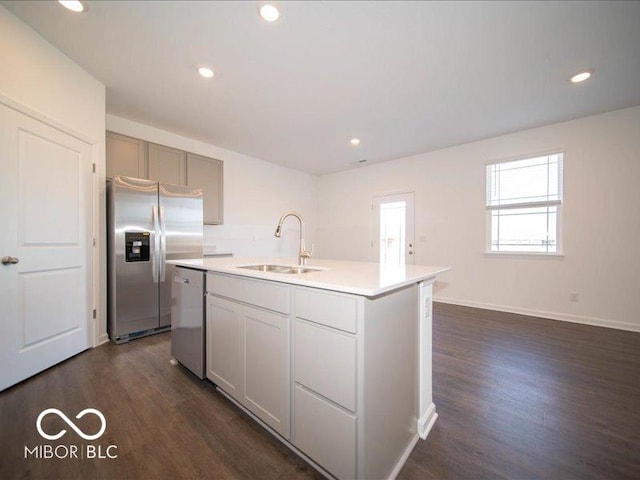 kitchen featuring dark wood-type flooring, sink, gray cabinets, an island with sink, and stainless steel appliances