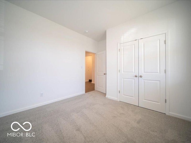 unfurnished bedroom featuring light colored carpet and a closet