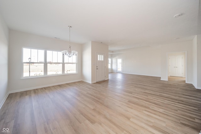 unfurnished living room with light hardwood / wood-style floors and a chandelier