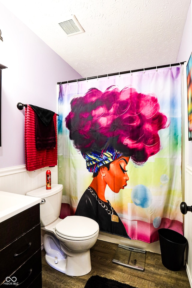 bathroom with a textured ceiling, hardwood / wood-style flooring, vanity, and toilet