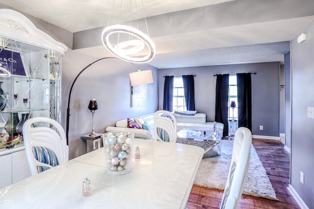 dining room with wood-type flooring, an inviting chandelier, and a textured ceiling