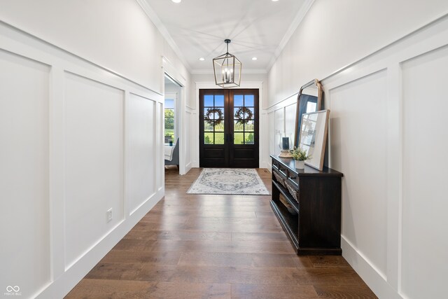 entrance foyer featuring an inviting chandelier, ornamental molding, dark hardwood / wood-style floors, and french doors