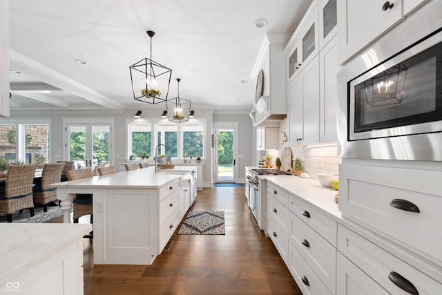 kitchen with stainless steel appliances, white cabinetry, a healthy amount of sunlight, and a breakfast bar area