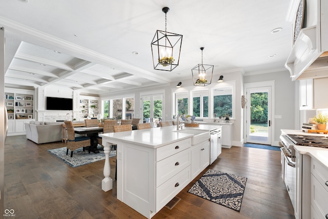 kitchen with white cabinets, an island with sink, dark wood-type flooring, appliances with stainless steel finishes, and a kitchen breakfast bar