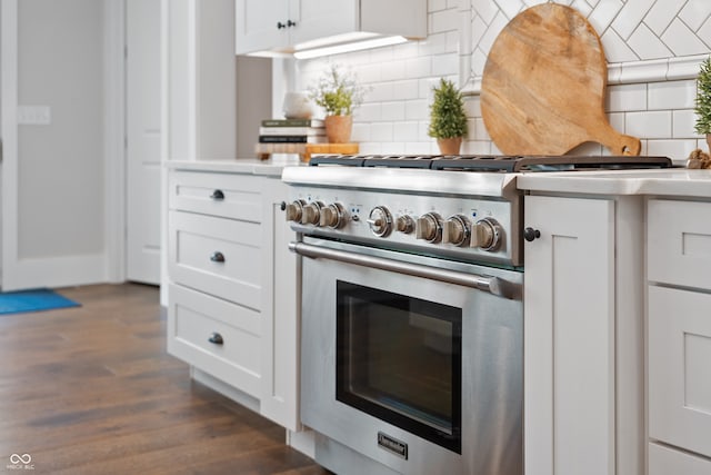 kitchen with stainless steel stove, white cabinets, dark wood-type flooring, and decorative backsplash