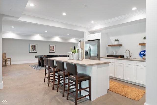 kitchen with an island with sink, stainless steel fridge, pool table, and white cabinetry