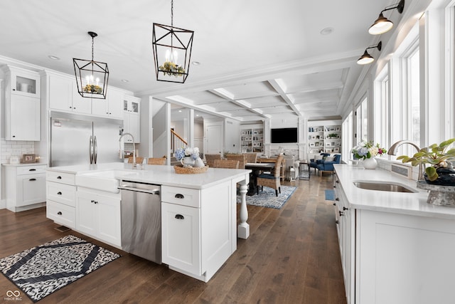 kitchen with appliances with stainless steel finishes, a kitchen island with sink, white cabinetry, and sink