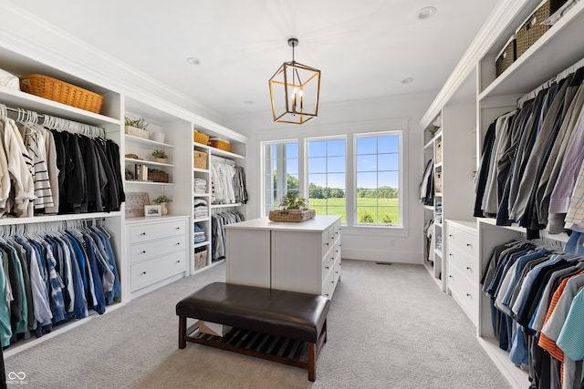 walk in closet featuring light colored carpet and a chandelier