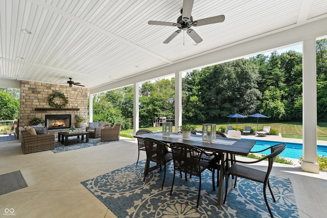 view of patio with an outdoor living space with a fireplace and ceiling fan