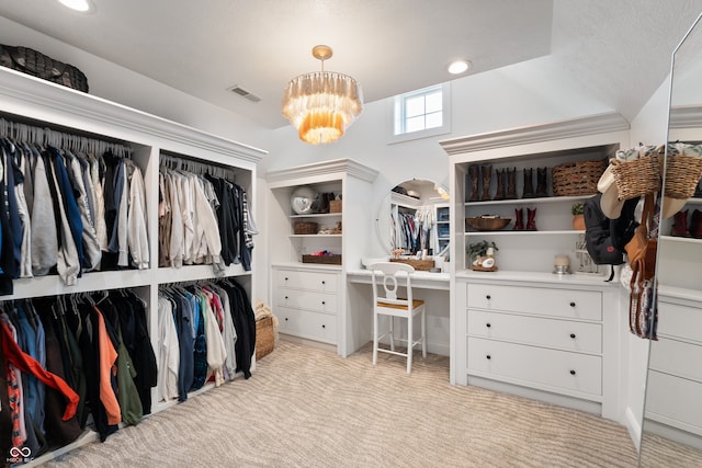 walk in closet featuring light carpet and an inviting chandelier