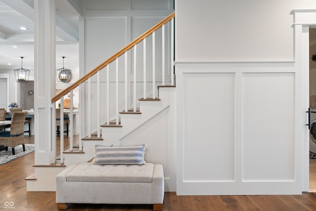 staircase featuring a chandelier, hardwood / wood-style flooring, and washer / dryer