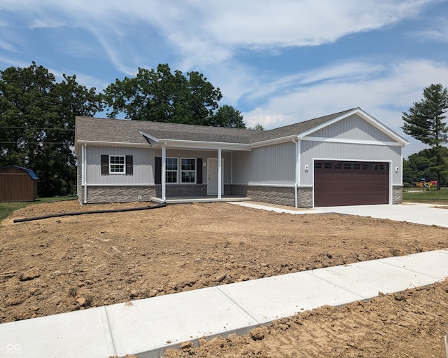 single story home with a garage, a storage unit, and covered porch