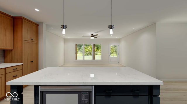 kitchen with ceiling fan, decorative light fixtures, light wood-type flooring, and a kitchen island