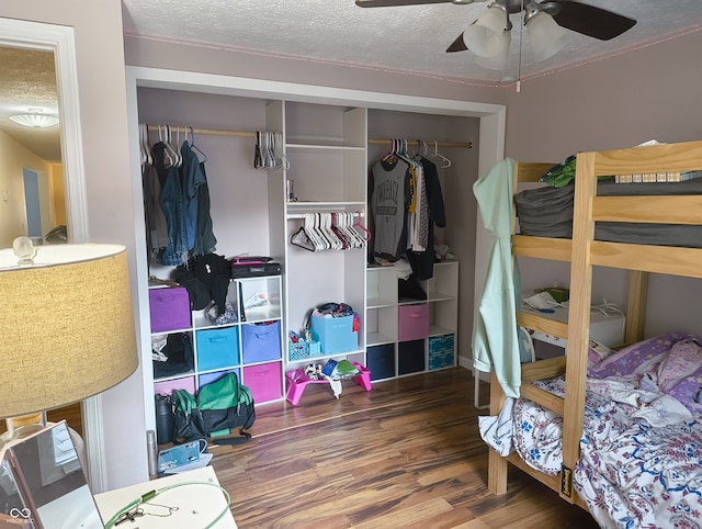 bedroom with ceiling fan, hardwood / wood-style flooring, a closet, and a textured ceiling