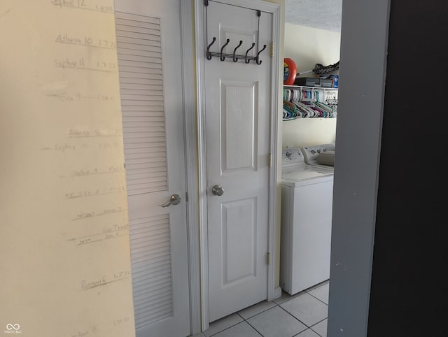 laundry area with washing machine and clothes dryer, a textured ceiling, and light tile patterned floors