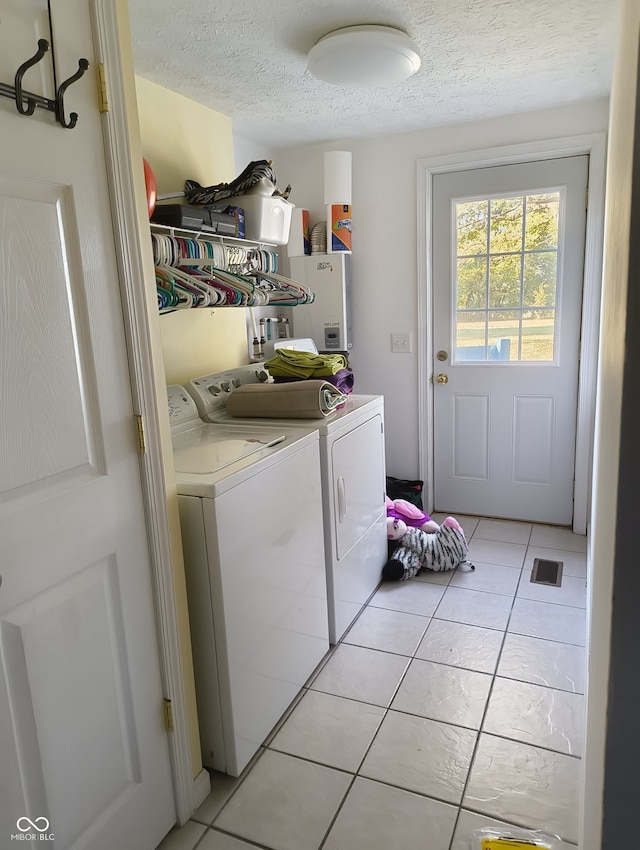 laundry room with separate washer and dryer, light tile patterned floors, and a textured ceiling