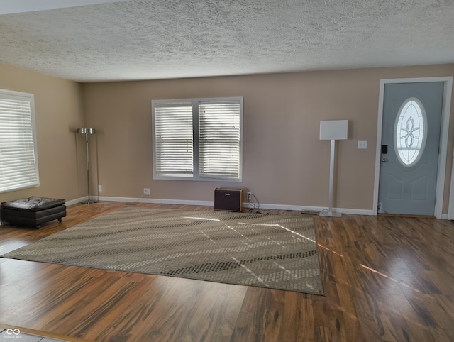 entryway featuring dark wood-type flooring and a textured ceiling