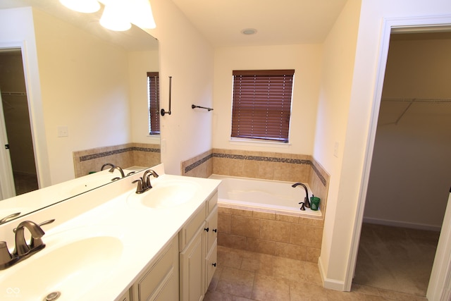 bathroom featuring tile patterned flooring, vanity, and tiled bath