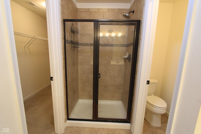 bathroom featuring a shower with door and toilet