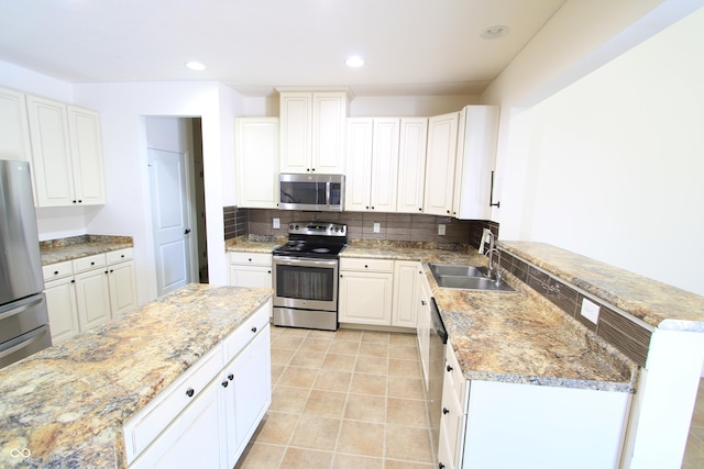 kitchen featuring sink, white cabinetry, light tile patterned floors, stainless steel appliances, and backsplash