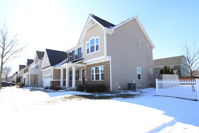 snow covered property featuring a garage and central air condition unit