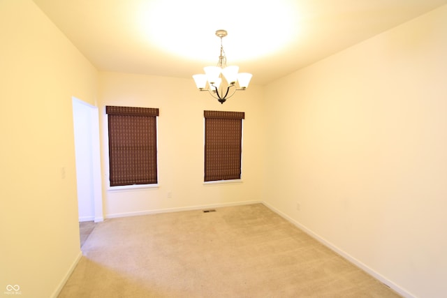 carpeted empty room featuring a chandelier