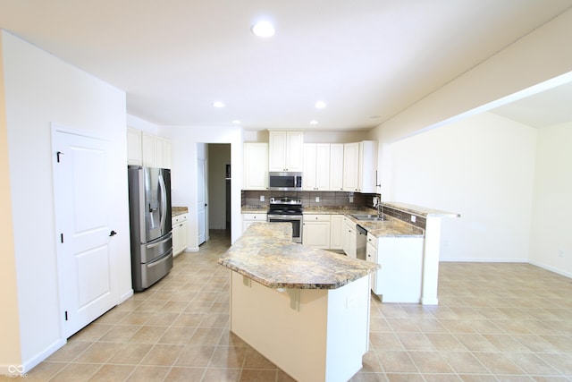 kitchen with sink, a breakfast bar area, appliances with stainless steel finishes, tasteful backsplash, and white cabinets