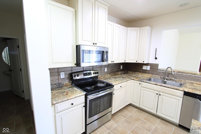 kitchen with appliances with stainless steel finishes, sink, white cabinets, and backsplash