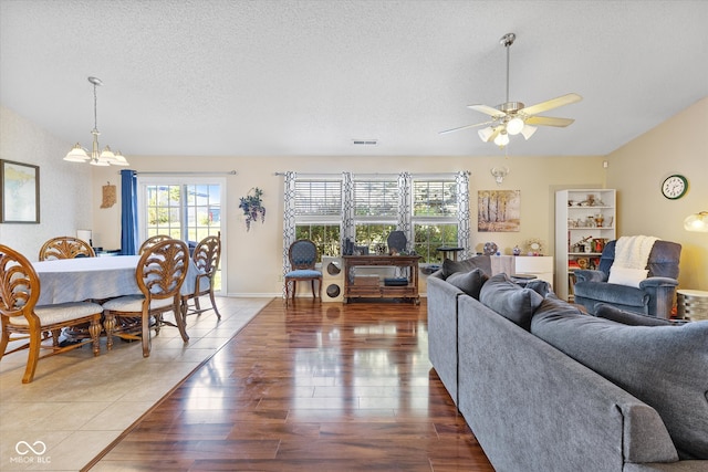 living room featuring a textured ceiling, ceiling fan with notable chandelier, and hardwood / wood-style flooring