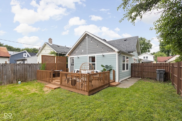 rear view of house featuring a lawn and a deck