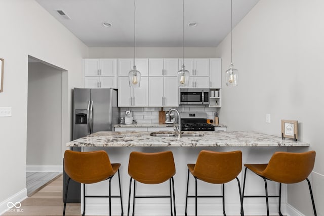 kitchen featuring sink, white cabinetry, kitchen peninsula, decorative backsplash, and appliances with stainless steel finishes