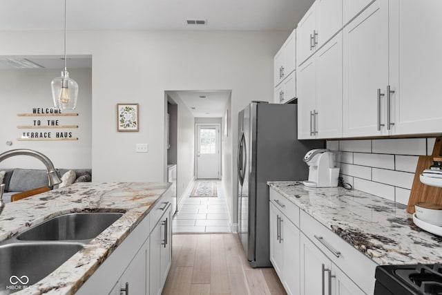 kitchen featuring white cabinets, sink, tasteful backsplash, light hardwood / wood-style flooring, and light stone countertops