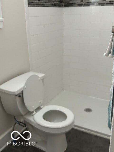 bathroom featuring a tile shower and toilet