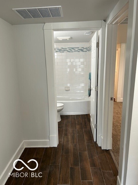 bathroom featuring hardwood / wood-style floors, toilet, and tiled shower / bath combo