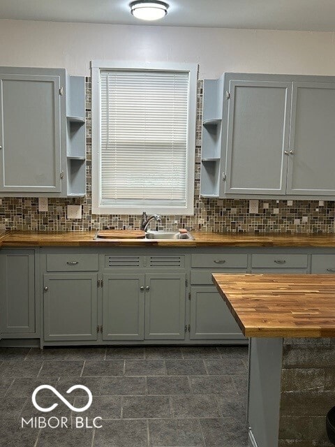 kitchen with gray cabinetry, wooden counters, sink, and tasteful backsplash