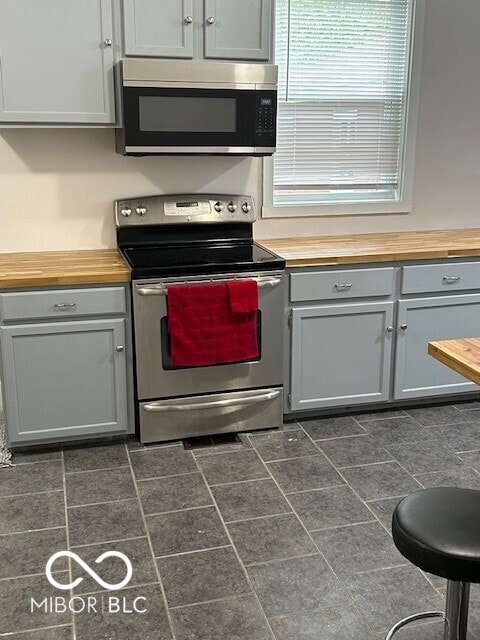 kitchen featuring gray cabinets, appliances with stainless steel finishes, and butcher block counters