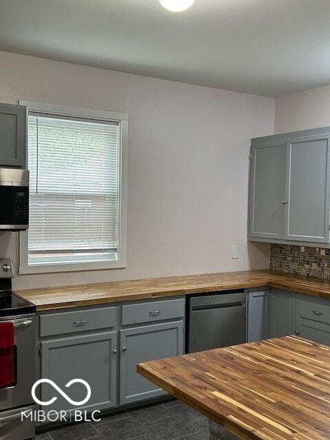 kitchen featuring gray cabinets, wooden counters, stainless steel appliances, and backsplash