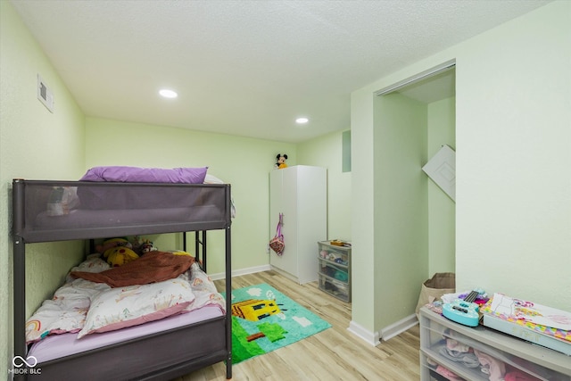 bedroom with a textured ceiling and light wood-type flooring