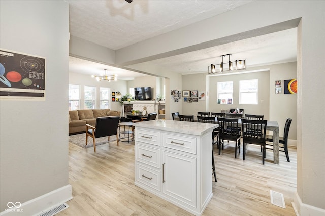 kitchen featuring a textured ceiling, pendant lighting, light hardwood / wood-style flooring, and white cabinets