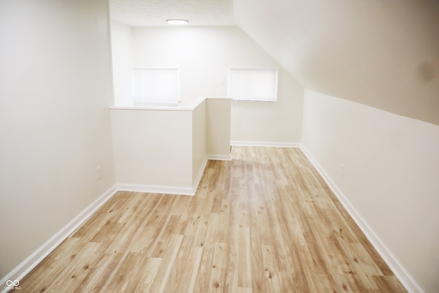 additional living space with light hardwood / wood-style flooring and lofted ceiling