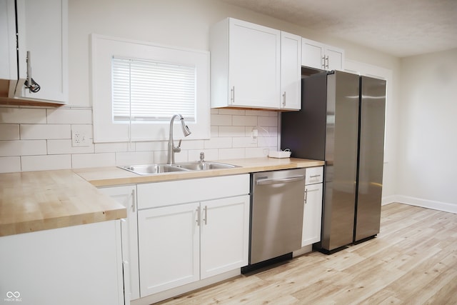 kitchen with appliances with stainless steel finishes, white cabinets, wooden counters, light hardwood / wood-style flooring, and sink