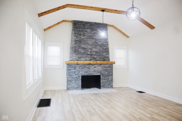 unfurnished living room with a fireplace, ceiling fan, beamed ceiling, and a wealth of natural light