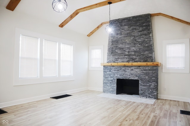 unfurnished living room with high vaulted ceiling, light hardwood / wood-style floors, beamed ceiling, and a stone fireplace