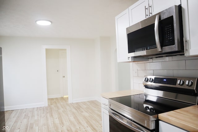 kitchen featuring wooden counters, light hardwood / wood-style flooring, white cabinetry, appliances with stainless steel finishes, and decorative backsplash