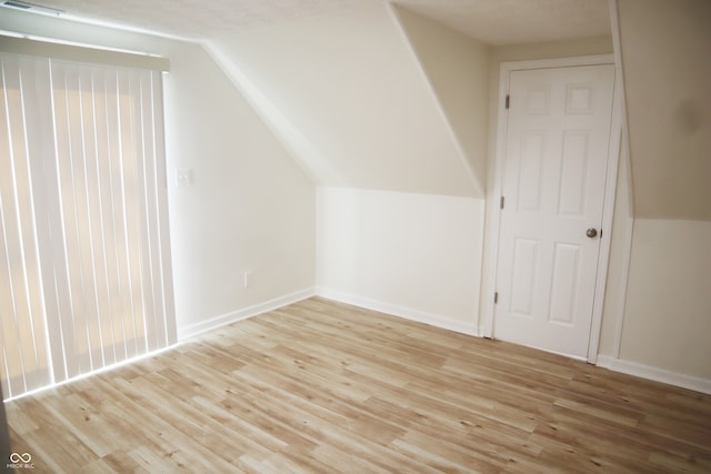 bonus room featuring light hardwood / wood-style flooring, vaulted ceiling, and a textured ceiling