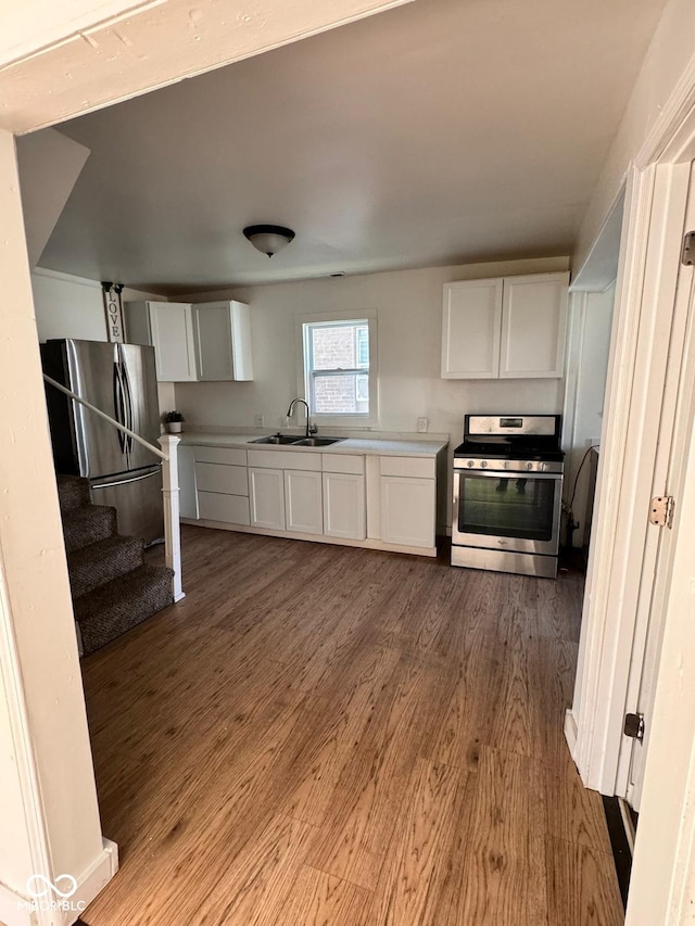 kitchen featuring appliances with stainless steel finishes, hardwood / wood-style floors, sink, and white cabinets