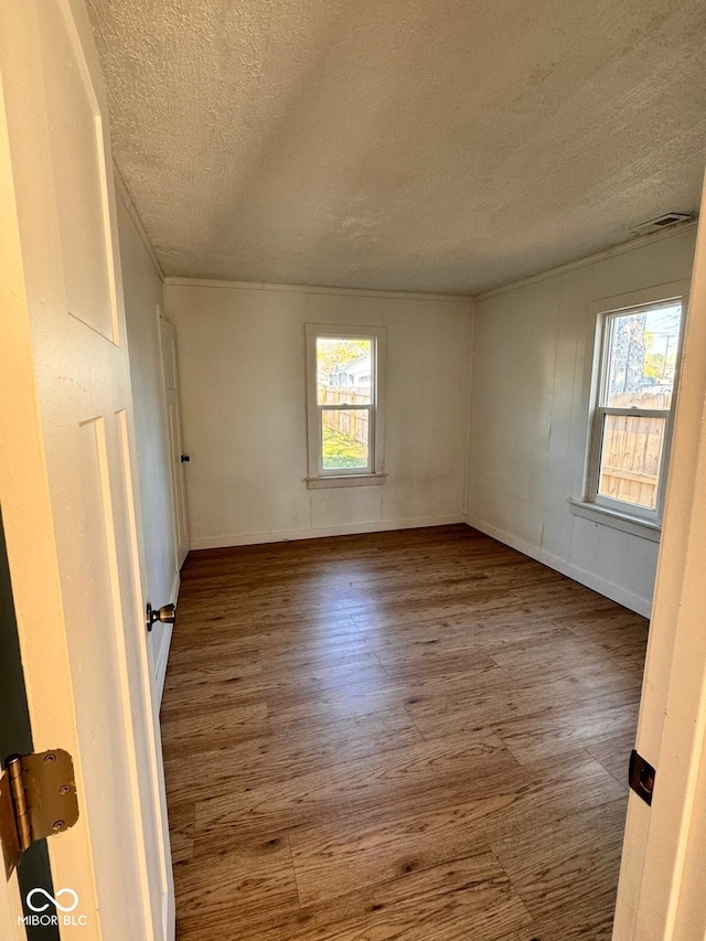 empty room with a textured ceiling and wood-type flooring